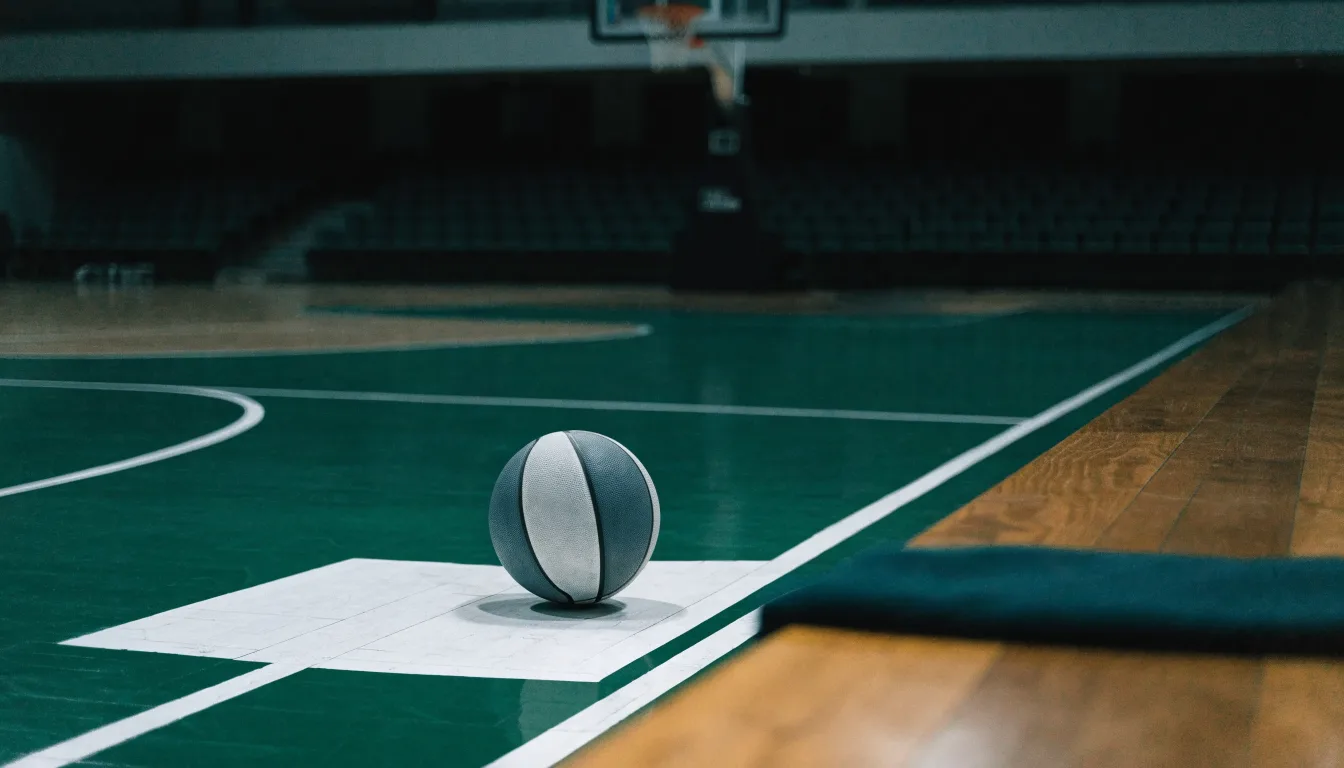 Ein Basketball liegt auf der Freiwurflinie einer Halle, im Vordergrund ein Handtuch auf einer Bank.