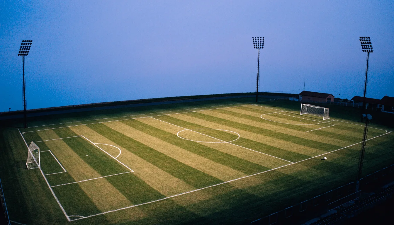 Ein Fußballplatz am Abend aus der Vogelperspektive, Flutlichtmasten ausgeschaltet, die Rasenlinien deutlich sichtbar.